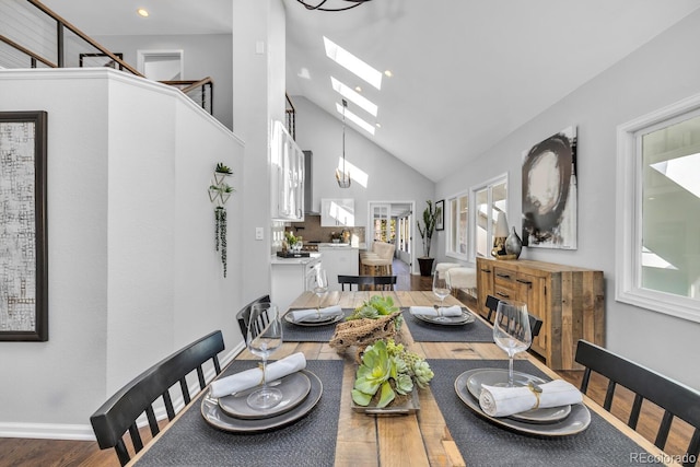 dining area with hardwood / wood-style floors, a skylight, and high vaulted ceiling