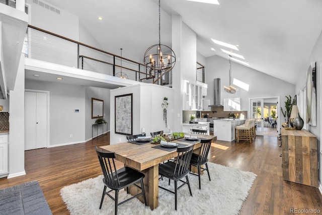 dining space featuring a high ceiling, a notable chandelier, dark hardwood / wood-style flooring, and a skylight