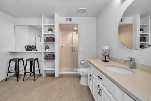 bathroom with vanity, toilet, a shower with shower door, and wood-type flooring