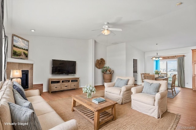 living room with ceiling fan, a tile fireplace, and light wood-type flooring