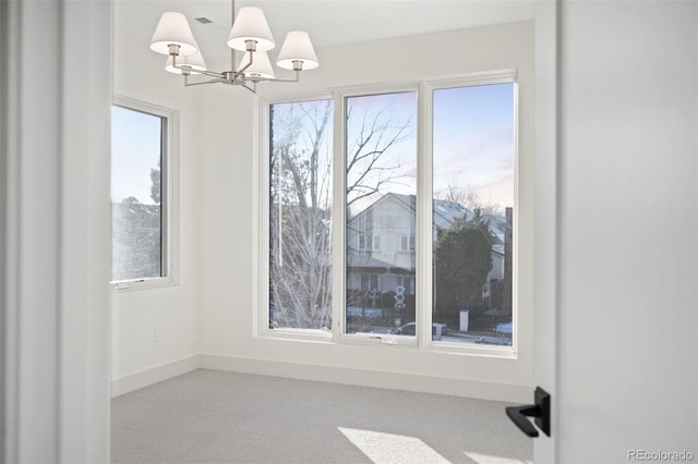 unfurnished dining area featuring light carpet and an inviting chandelier