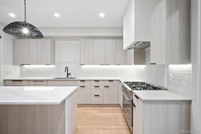 kitchen featuring light stone counters, sink, decorative light fixtures, high end stainless steel range, and light hardwood / wood-style floors