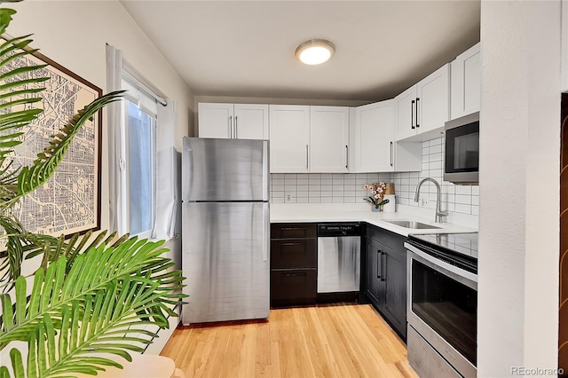 kitchen featuring a sink, stainless steel appliances, light countertops, tasteful backsplash, and light wood-type flooring