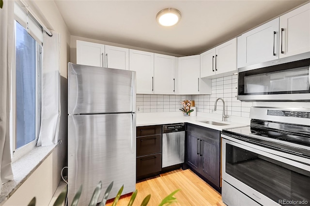 kitchen with light countertops, decorative backsplash, appliances with stainless steel finishes, white cabinetry, and a sink