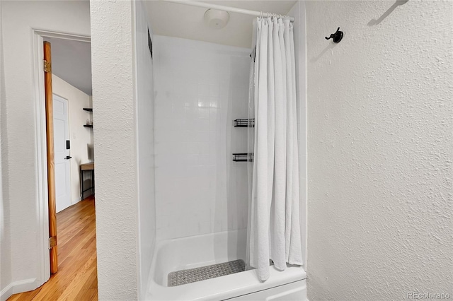 bathroom with a textured wall and wood finished floors