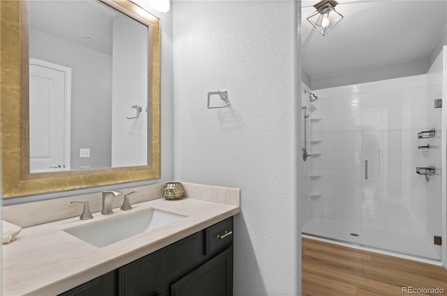 14300 Waterside Ln Unit E3, Broomfield, CO 80023 - bathroom featuring vanity, a shower stall, a textured wall, and wood finished floors