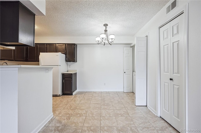 kitchen featuring dark brown cabinetry, a notable chandelier, freestanding refrigerator, decorative light fixtures, and visible vents