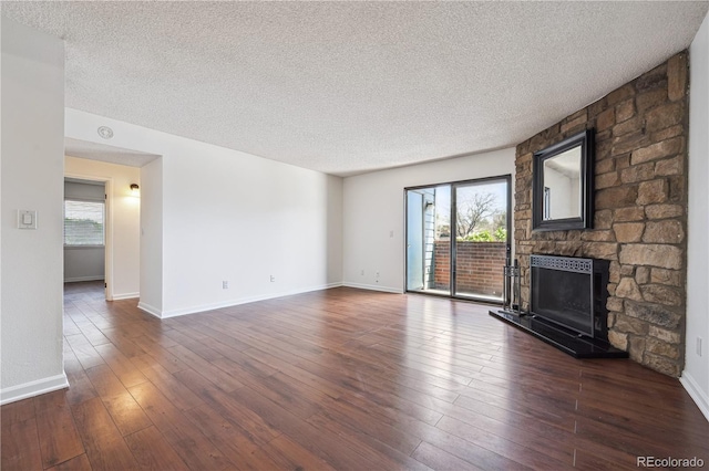 unfurnished living room featuring a fireplace, dark wood-type flooring, a textured ceiling, and a wealth of natural light