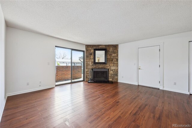 12037 E Harvard Ave Unit 104, Aurora, CO 80014 - unfurnished living room with dark wood-style flooring, a textured ceiling, baseboards, and a fireplace