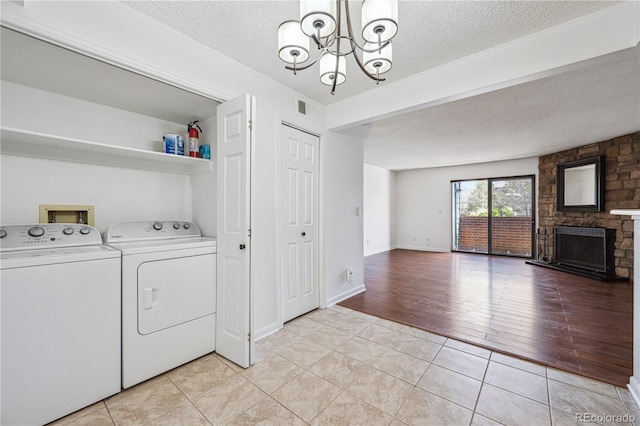 clothes washing area with washing machine and clothes dryer, laundry area, a textured ceiling, and a notable chandelier