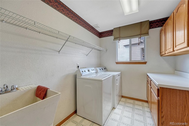 laundry room featuring cabinet space, baseboards, washing machine and clothes dryer, light floors, and a sink