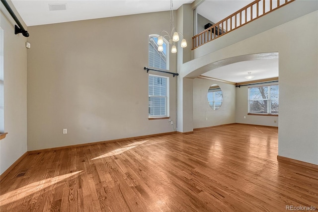 interior space featuring arched walkways, high vaulted ceiling, wood finished floors, baseboards, and an inviting chandelier