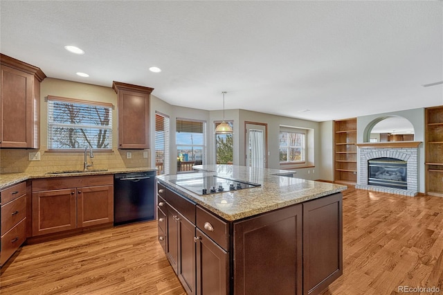 kitchen with light wood-style floors, a sink, light stone counters, and black appliances