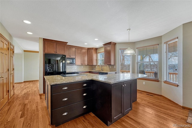 kitchen with decorative backsplash, a kitchen island, light wood-style flooring, and black appliances