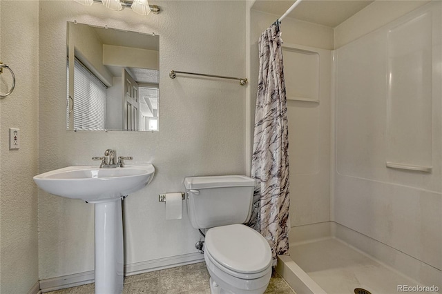 bathroom featuring a stall shower, baseboards, a textured wall, and toilet