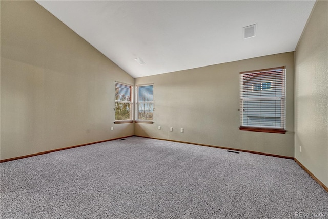 empty room with lofted ceiling, carpet flooring, visible vents, and baseboards