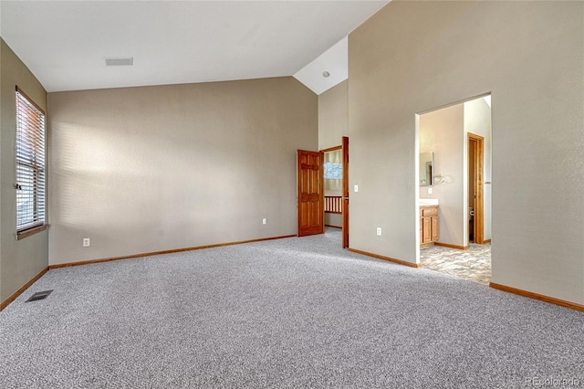 empty room featuring high vaulted ceiling, light colored carpet, visible vents, and baseboards