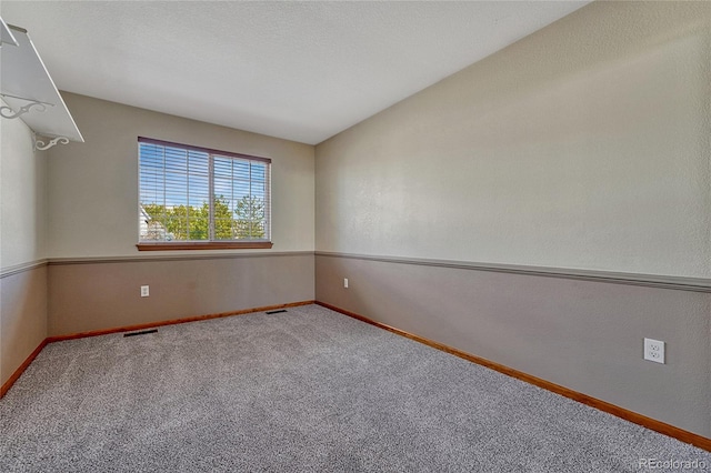 carpeted empty room with baseboards, visible vents, and a textured ceiling