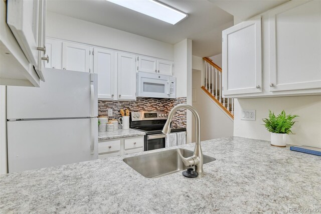 kitchen featuring decorative backsplash, white appliances, white cabinetry, and sink