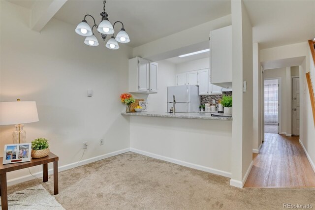 kitchen with pendant lighting, an inviting chandelier, white refrigerator, light wood-type flooring, and white cabinetry