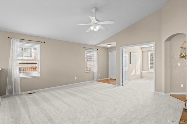 spare room with light colored carpet, vaulted ceiling, ceiling fan, and a healthy amount of sunlight