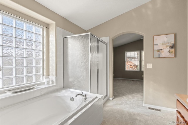 bathroom featuring vanity, vaulted ceiling, and independent shower and bath