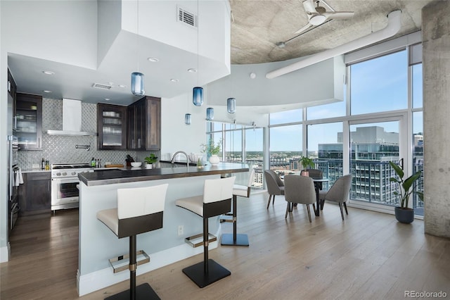 1700 Bassett St Unit 2315, Denver, CO 80202 - kitchen with wall chimney range hood, high end range, dark wood finished floors, floor to ceiling windows, and a kitchen bar