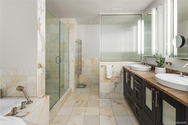 1700 Bassett St Unit 2315, Denver, CO 80202 - full bathroom with a towel warming rack, a bath, a stall shower, tile walls, and double vanity