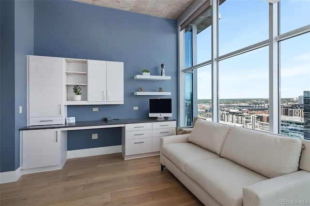 1700 Bassett St Unit 2315, Denver, CO 80202 - home office featuring built in study area, light wood-style floors, a wall of windows, and a towering ceiling