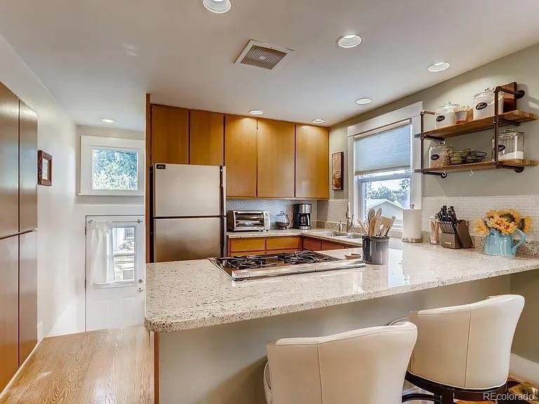 4654 Bryant St, Denver, CO 80211 - kitchen featuring appliances with stainless steel finishes, a peninsula, plenty of natural light, light wood finished floors, and recessed lighting