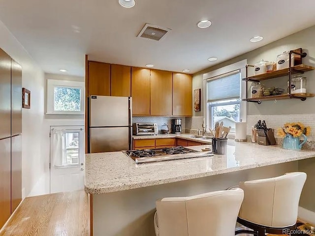 4654 Bryant St, Denver, CO 80211 - kitchen featuring appliances with stainless steel finishes, a peninsula, plenty of natural light, light wood finished floors, and recessed lighting