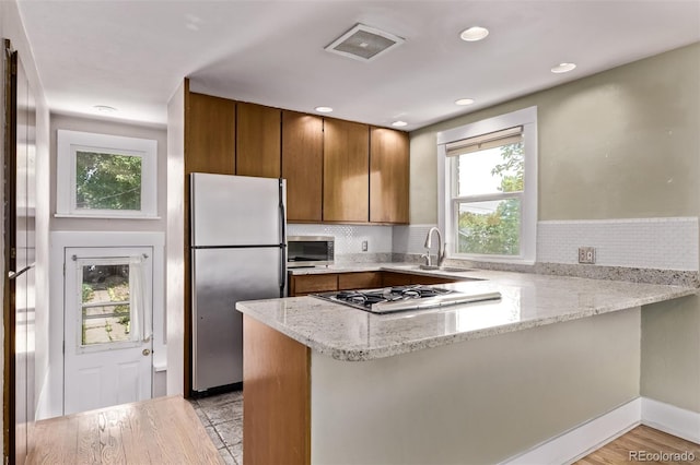 4654 Bryant St, Denver, CO 80211 - kitchen with appliances with stainless steel finishes, a peninsula, brown cabinets, plenty of natural light, and recessed lighting
