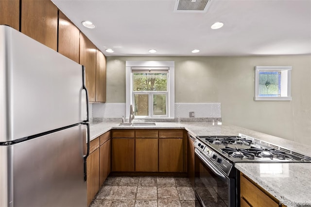 4654 Bryant St, Denver, CO 80211 - kitchen featuring freestanding refrigerator, gas stove, brown cabinetry, recessed lighting, and light stone countertops