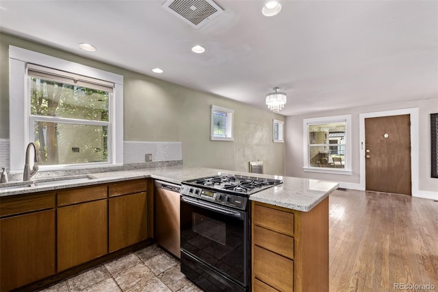 4654 Bryant St, Denver, CO 80211 - kitchen with gas stove, a peninsula, stainless steel dishwasher, light stone countertops, and brown cabinets