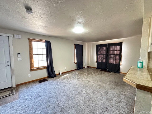 unfurnished living room featuring carpet and a textured ceiling