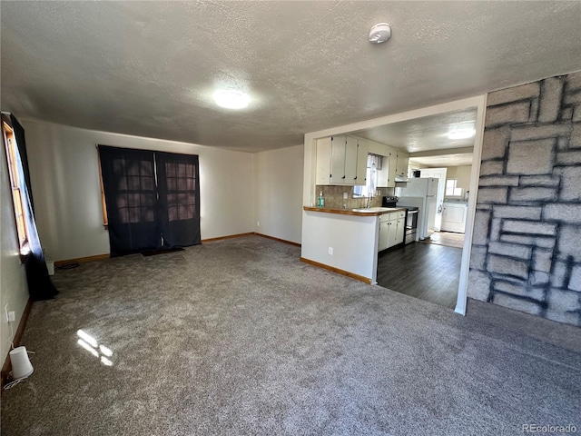 unfurnished living room featuring a textured ceiling, dark carpet, washer / clothes dryer, and sink