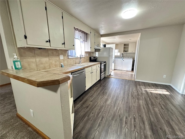 kitchen featuring separate washer and dryer, stainless steel appliances, sink, kitchen peninsula, and tile countertops