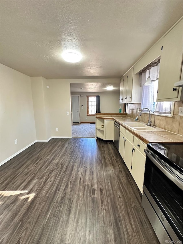 kitchen featuring appliances with stainless steel finishes, a healthy amount of sunlight, dark hardwood / wood-style flooring, and sink