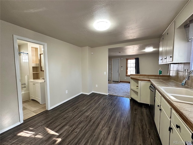 kitchen featuring a textured ceiling, tile counters, sink, dark hardwood / wood-style floors, and kitchen peninsula