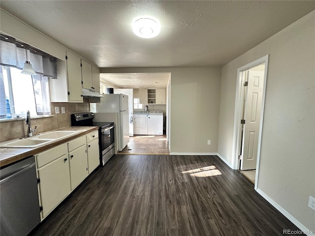 kitchen featuring washer and clothes dryer, appliances with stainless steel finishes, white cabinetry, dark hardwood / wood-style flooring, and sink