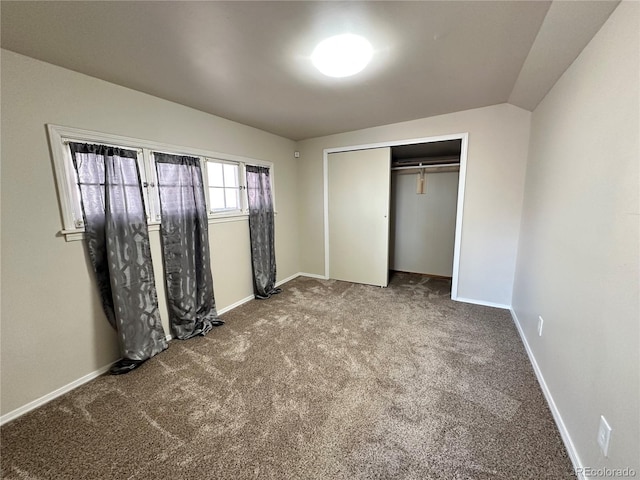 unfurnished bedroom with vaulted ceiling, a closet, and carpet flooring