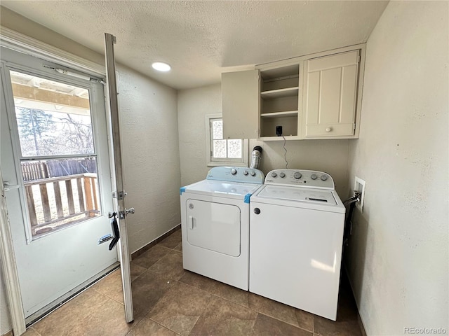 laundry room with a wealth of natural light, separate washer and dryer, a textured ceiling, and cabinets