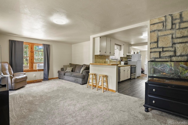 living room featuring cooling unit, a textured ceiling, and dark colored carpet