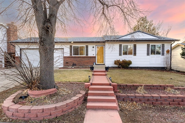 ranch-style home with a garage, brick siding, and a front yard