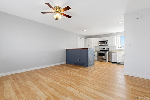 kitchen featuring white cabinets, light wood-style flooring, baseboards, and stainless steel appliances