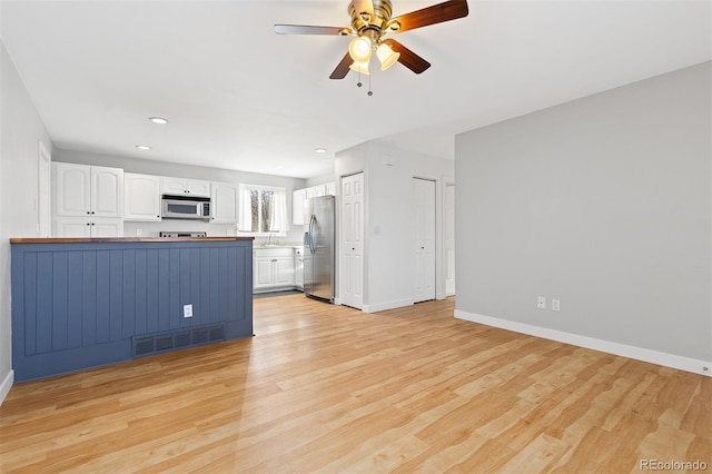 kitchen featuring stainless steel appliances, light wood-type flooring, white cabinetry, and visible vents