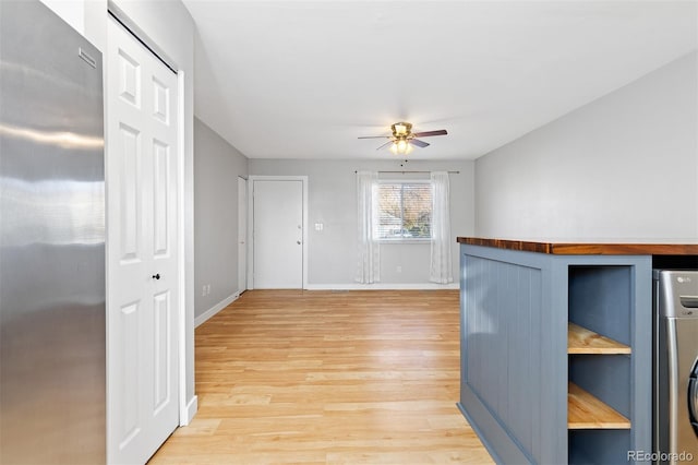 interior space with light wood finished floors, a ceiling fan, and baseboards