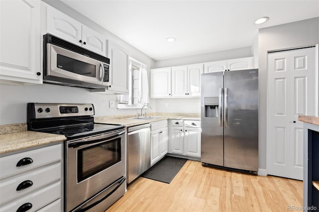 kitchen featuring stainless steel appliances, light wood-type flooring, light countertops, and white cabinetry