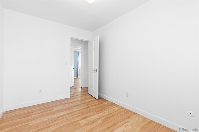 spare room with baseboards and wood finished floors