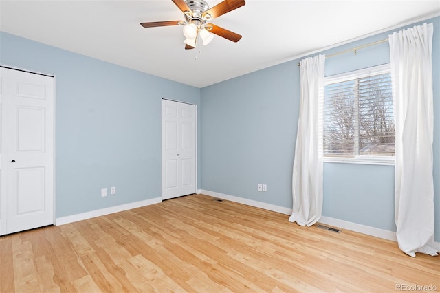 unfurnished bedroom featuring baseboards, visible vents, ceiling fan, and wood finished floors